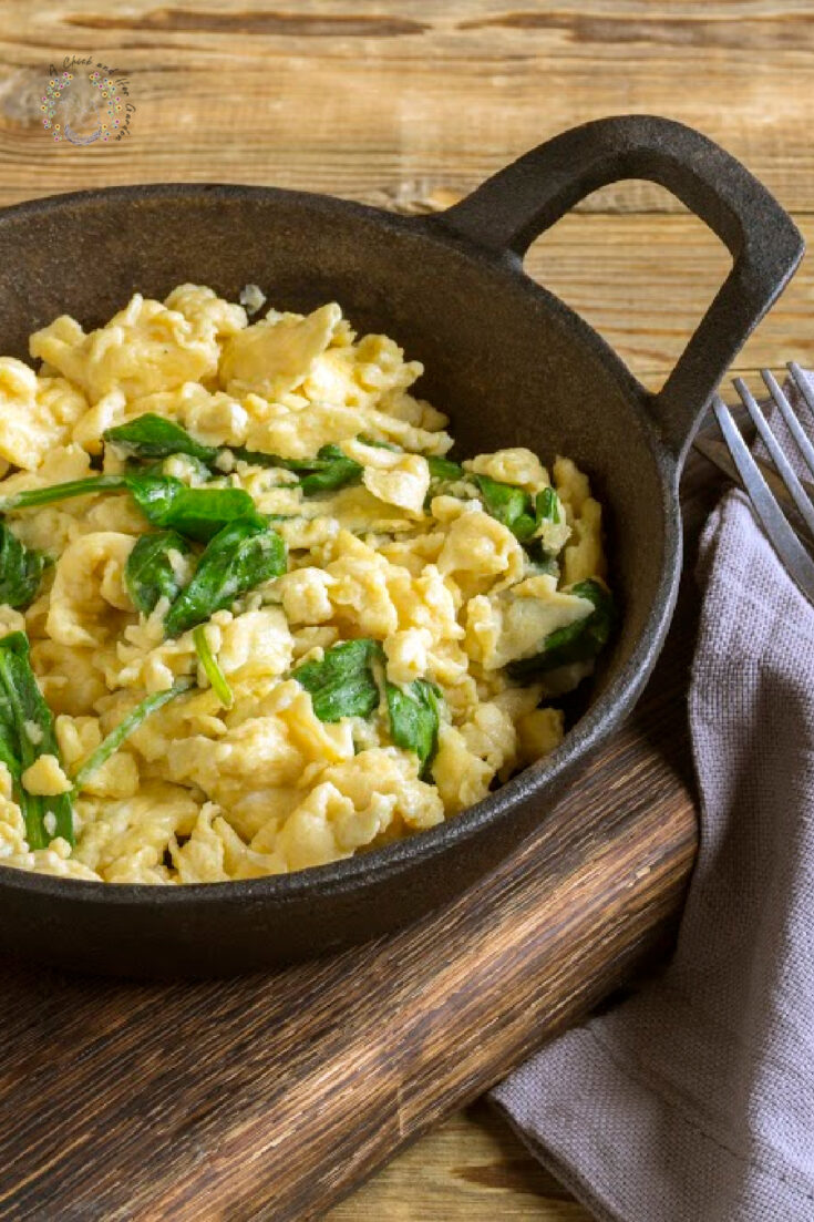 scrambled eggs with spinach in a cast-iron pan. on a wooden table