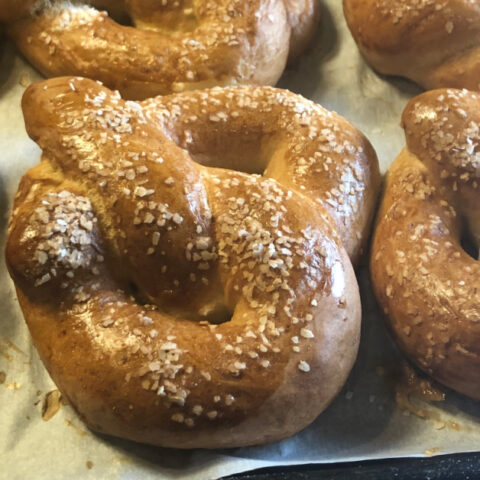 close up of soft sourdough pretzels on a baking sheet