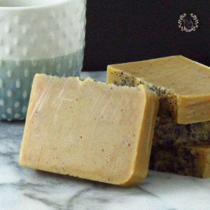 four bars of pumpkin coffee soap stacked on a marble surfacewith a blue and white mug in the background