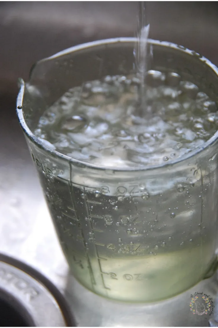 plastic liquid measuring cup in a sink being filled with water