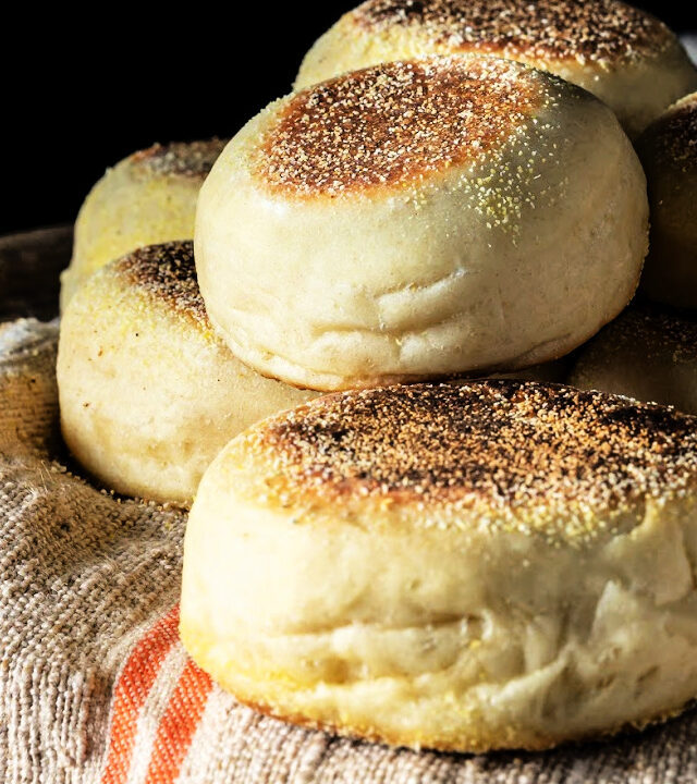 five english muffins stacked on a white towel with orange stripes and a black backdrop